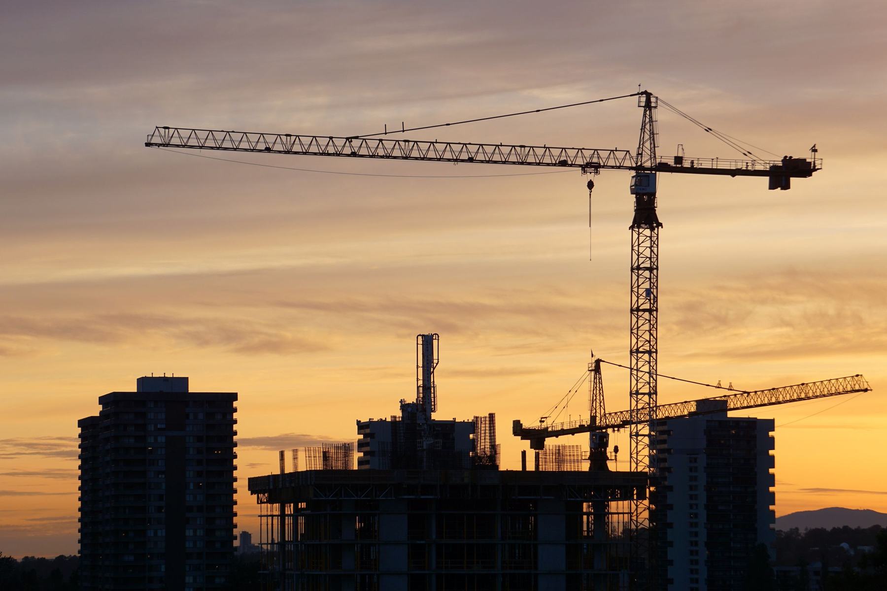 Tower cranes over a building under construction at dusk